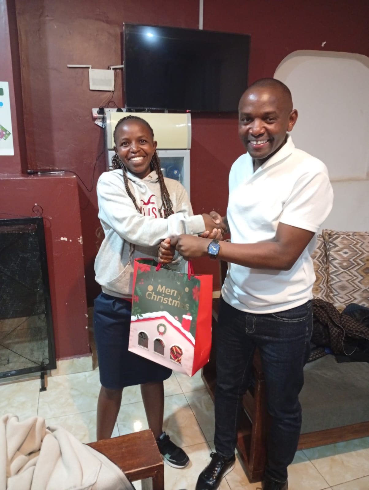 A smiling Mwita & Co. team member receiving a festive gift bag during an office celebration.
